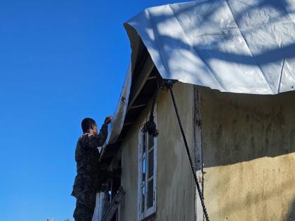 A member of the JDF assists with the laying of a tarpaulin on a roof in Granville, Trelawny last week
