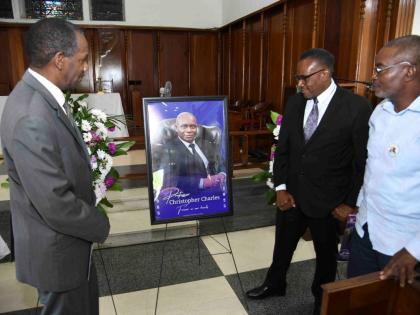 Neville Robinson (left), Trevor Scott (centre) and Lionel Dillon, members of Kingston College’s Class of 1981, look at a portrait of their late batchmate, Professor Christopher Charles, during a thanksgiving service for his life held yesterday at the Uni