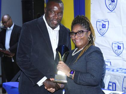 Mount Pleasant Football Academy head coach, former national player Theodore Whitmore (left), receives the Abe Alexander Award for Excellence from assistant general secretary Karen Bogle at the Kingston and St Andrew Business House Football Association’s 