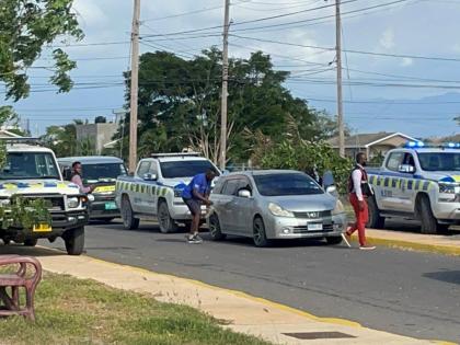 Police examine the scene of yesterday’s fatal shoot-out at Phoenix Park Village in Phase 3, Portmore, St Catherine, where a police operation left one alleged robber dead and another on the run. 