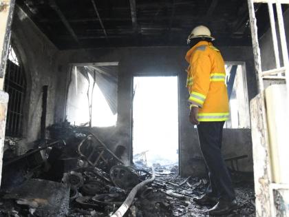 A firefighter surveys the charred remnants of Ray Moore’s home on Mountain View Avenue in St Andrew yesterday. Several burnt speaker parts can be seen scattered about.