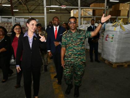 Minister of Foreign Affairs and Foreign Trade, Senator Kamina Johnson Smith (left), looks on as Colonel General Staff, Guyana Defence Force, Captain Vernon Burnette, points out hurricane relief items donated by Guyana, including roofing material for the re