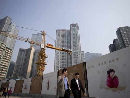 In this October 8, 2013, file photo, office workers walk past ‘China Dream’ message boards at a construction site.