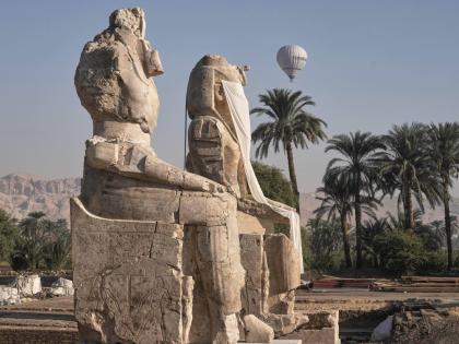 A hot-air balloon flies over the assembly of two giant alabaster statues for Pharaoh Amenhotep III, before the official opening, in the southern city of Luxor, Egypt.