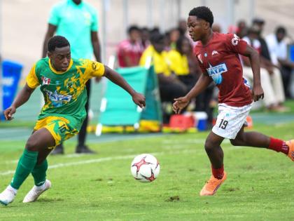 Excelsior High School’s Damarley Williams (left) rounds Eltham High School’s Kevin Clarke during the ISSA/WATA Manning Cup semi-finals at the National Stadium yesterday.