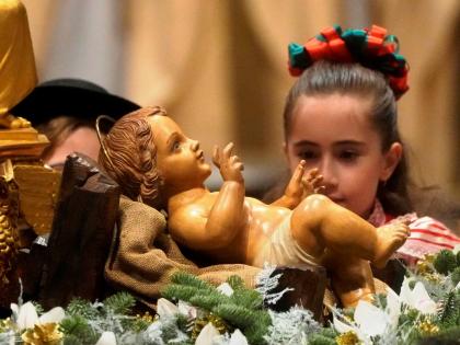 In this December 2022 photo a girl looks at a statue of Baby Jesus as Pope Francis presides over Christmas Eve Mass, at St. Peter’s Basilica at the Vatican.