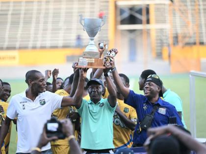 Coach of Clarendon College, Devon Anderson (centre), holds aloft the Ben Francis Cup football trophy after his team defeated Cornwall College 2-1 at the National Stadium on December 20, 2025.