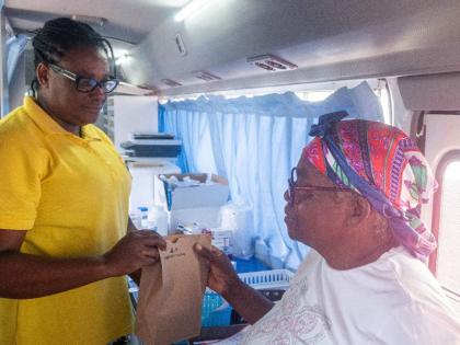 Robertha Carter (left), pharmacy technician, National Health Fund, presents to Dorrett Burton her free prescription drugs after seeing the doctor at the Hurricane Recovery Health Clinic in Thornton, St Elizabeth.