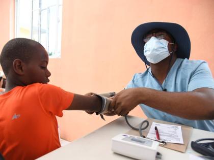 Alex Johnson, head of the Faith Chapel of Faith Apostolic Ministries Health and Welness Department, attends to a patient on December 13 at the Mother Lewis AME Church in Shrewsbury, Westmoreland. 