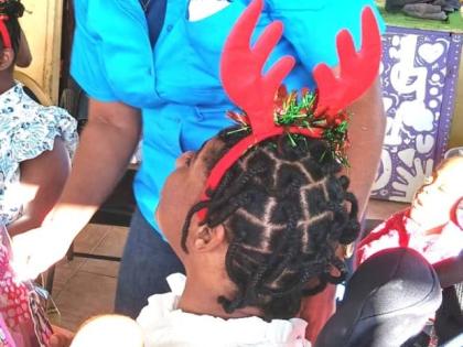 Naudia Crosskill, chief executive officer, St James Municipal Corporation, sharing pleasantries with a female ward at the Mustard Seed Children’s Home in Moore Park, St James at their annual Christmas treat. 