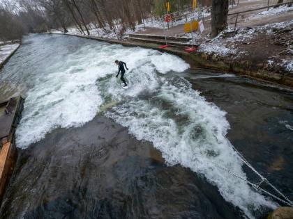 A man tries out the temporary Eisbach wave in the English Garden in Munich, Germany.