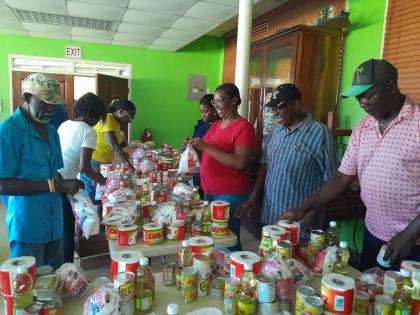 A group of community leaders and employees of Discovery Bauxite prepare 500 care packages for Hurricane Melissa victims.