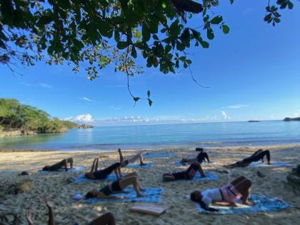Mat and Flow attendees engage in a glute bridge with extended arms at Winnifred Beach, Portland.