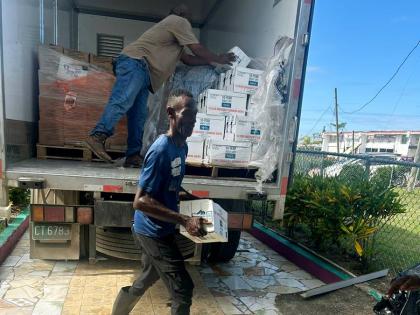 Volunteers unpack water and meals donated by Olympian Claston Bernard and the JN Foundation.
