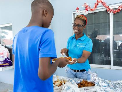 Friends Who Care founding member Roxanne Isaacs serves a youngster from the Mustard Seed Children’s Home a meal during the annual holiday treat.