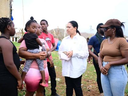 Custos of Clarendon Edith Chin (second right) speaks with Ashella Baker (second left) from Middle Quarters in St Elizabeth, while in the community recently to hand over a container house to the mother of six. Sharing in the discussion is representative of 