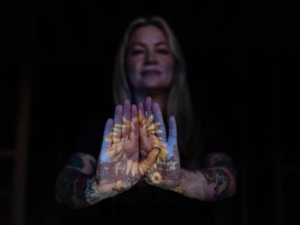 A photo of sunflowers Missi Dowd-Figueroa once grew on her property is projected onto her palms as she poses for a portrait at her rebuilding site in Altadena, California.