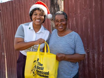 All smiles from Moya Williams (right) of the McCook’s Pen community as she receives her Best Dressed Chicken goodie bag from Loren Lee (left), internal communications & engagement officer at Jamaica Broilers Group, during the company’s recent outreach 