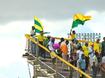 Fans of Excelsior High wave flags with the school’s colours during the Olivier Shield playoff against St Elizabeth Technical High at the Stadium East football field on Thursday.