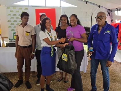 
Jamaica Athletics Administrative Association First Vice-President Ian Forbes (right) looks on as PUMA marketing manager for running, Juliet Campbell, presents a care package to a student from Rusea’s High School at the school’s grounds on Friday.