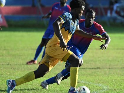 Racing United’s Marcovich Brown dribbles away from the pressure of Dunbeholden’s Ricardo Beckford during their Jamaica Premier League encounter at Ferdi Neita Park yesterday. The game ended 1-1.