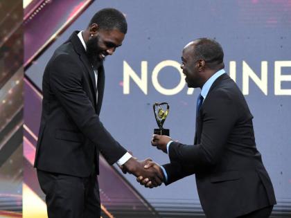 High jumper Raymond Richards (left) is presented with an award during the RJRGLEANER Communications Group National Sports Awards from Head of TV Business Ransford Ricketts at the TVJ Studios on Saturday. 