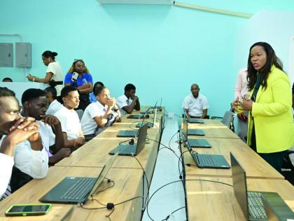 Permanent Secretary in the Ministry of Education, Skills, Youth and Information, Dr Kasan Troupe (right), engages with Bustamante High School students, during the handover of renovated and expanded information communications technology facilities at the in