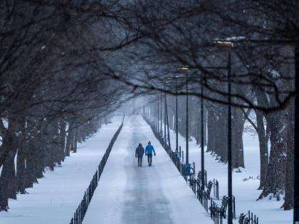 Two people walk along the National Mall as snow falls on January 25, 2026, in Washington. 