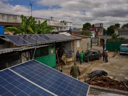 Solar panels cover the roof at the home of Felix Jose Morfi where mechanics push his broken down Lada car in Regla, Havana province, Cuba, Thursday, January 29, 2026. (AP Photo/Ramon Espinosa)