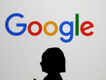 A woman walks by a giant screen with a logo at an event at the Paris Google Lab on the sidelines of the AI Action Summit in Paris on February 9, 2025. 