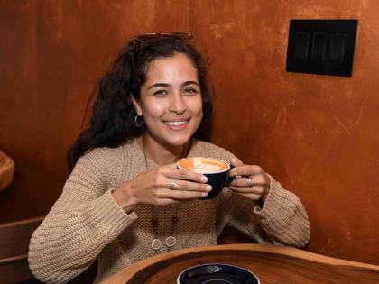 Project engineer Zoe Chang enjoys a cup of latte at the 
opening of Cafe Blue’s New Kingston location on Monday.  