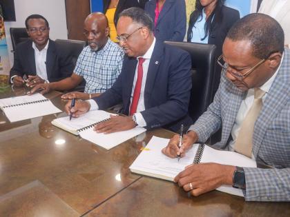 Jamaica Social Investment Fund (JSIF) Managing Director, Omar Sweeney (second right), affixes his signature to the contract to rehabilitate Bath Botanical Gardens in St Thomas, during a contract-signing ceremony on February 5 at JSIF’s Richmond Avenue of