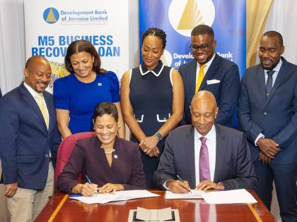 Gillian Hyde (front row left), deputy managing director, JN Bank, and Dr David Lowe, managing director, Development Bank of Jamaica (DBJ) sign a partnership agreement to help micro and small businesses affected by Hurricane Melissa to restore operations th