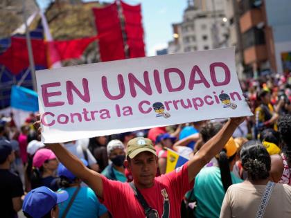 A government supporter holds a sign with a message that reads in Spanish: "In unity against corruption", during a rally against corruption, in Caracas, Venezuela, Saturday, March 25, 2023. (AP Photo/Matias Delacroix, File)