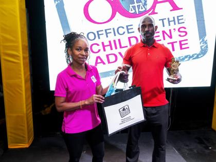 Ann Margaret Lim (left) from the Office of the Children’s Advocate, makes a presentation to Christopher Wilmot, the winner of the Burpees competition, during the 2026 FitFest Party & Expo (New Year Edition) on January 31 at the NWC Sports Club.