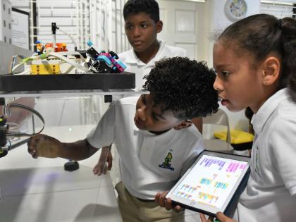 (From left): Jaxen Mitchell, Jacob Wong and Gia Whyms-Stone, members of Reach Academy robotics team, assembling a robot that won gold in the World Robotics Competition in 2024.