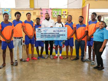 Chevon Lewis (centre), brand manager for MPowa at Wisynco, and Moniefa Morrison (right), brand ambassador, Wisynco, share a moment with the Tru Juice Football Club after handing over a symbolic cheque valued at $2.75 million on behalf of Wisynco brands —