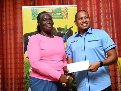Agriculture Minister Floyd Green presenting Novelette Moore, a St James banana farmer, with her Hurricane Melissa recovery assistance cheque on February 25.
