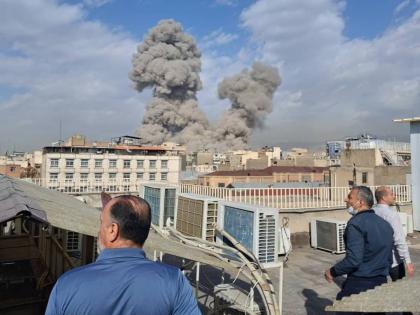 People watch as smoke rises on the skyline after an explosion in Tehran, Iran on February 28, 2026.