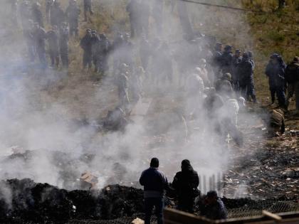 Investigators examine bank notes burned by authorities to prevent people from approaching the scene of a cargo plane that crashed on a highway on February 27, 2026, carrying money, in El Alto, Bolivia.  
