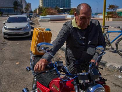 Retiree Jorge Reyes pushes his motorcycle to refuel as it's his turn in line at a gasoline station in Havana, Cuba.