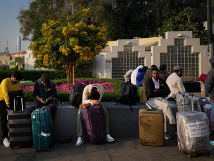 Passengers stranded by the closure of Dubai International Airport await for assistance in the airport parking lot in Dubai, United Arab Emirates on Sunday.