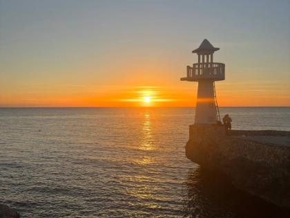 A sunset view with the Negril Lighthouse in the foreground, photographed from the Negril Huts property in West End.