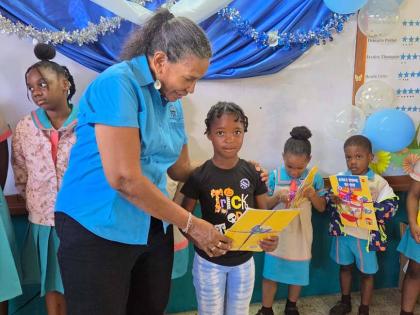 Colleen Wint-Bond, project coordinator at the Violence Prevention Alliance, presents gifts to a student at the Chalky Hill Primary and Infant School on National Peace Day.