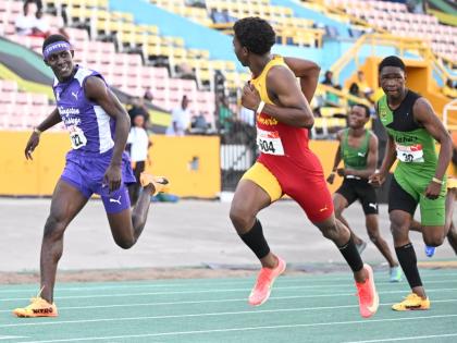 Mark-Daniel Allen (second from left) of Wolmer’s Boys’ glances at  Kingston College’s Brandon Bennett (left) as he powers to the line to win the boys’ under-17 110 metres hurdles  in 13.57 seconds at the Carifta Trials yesterday. 