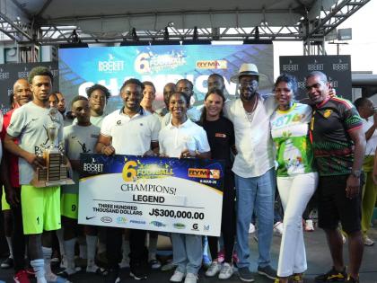 Former St Vincent and the Greandines national player Renson Haynes (right) and Shelly-Ann Fraser-Pryce (centre) help Legend celebrate winning the 10th Pocket Rocket Foundation Six-A-Side Football Competition at the Wray and Nephew football field on Sunday.