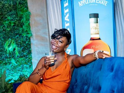 Accountant Jenelle Taylor is all smiles for the camera inside the Appleton Estate booth, wearing a burnt orange slip dress. 