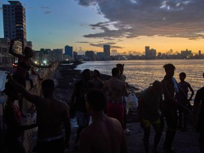 People watch the sunset from the Malecón during a blackout in Havana, Monday, March 16, 2026. 
