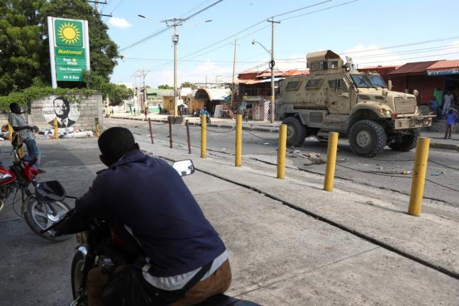 Residents watch a Kenyan police armoured vehicle patrolling in Port-au-Prince, Haiti, on September 2.