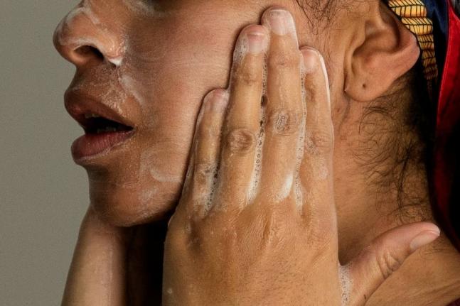 A woman washes her face as she prepares for work.